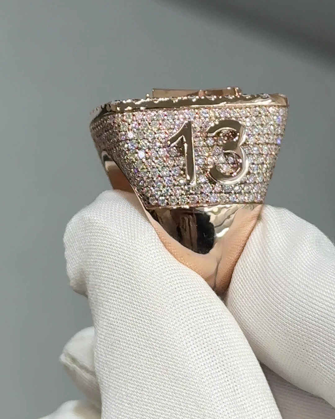 Side view of the finished rose gold championship-style ring with the number 13 on its diamond-set shoulder