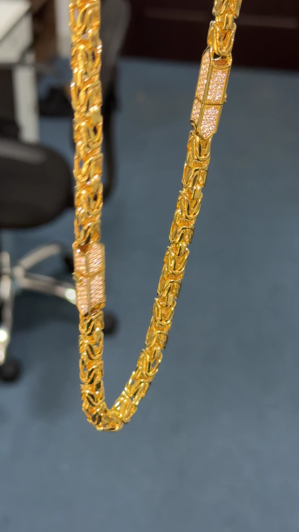 Joined 9K yellow gold Byzantine necklace with diamond-set links, held in a white-gloved hand