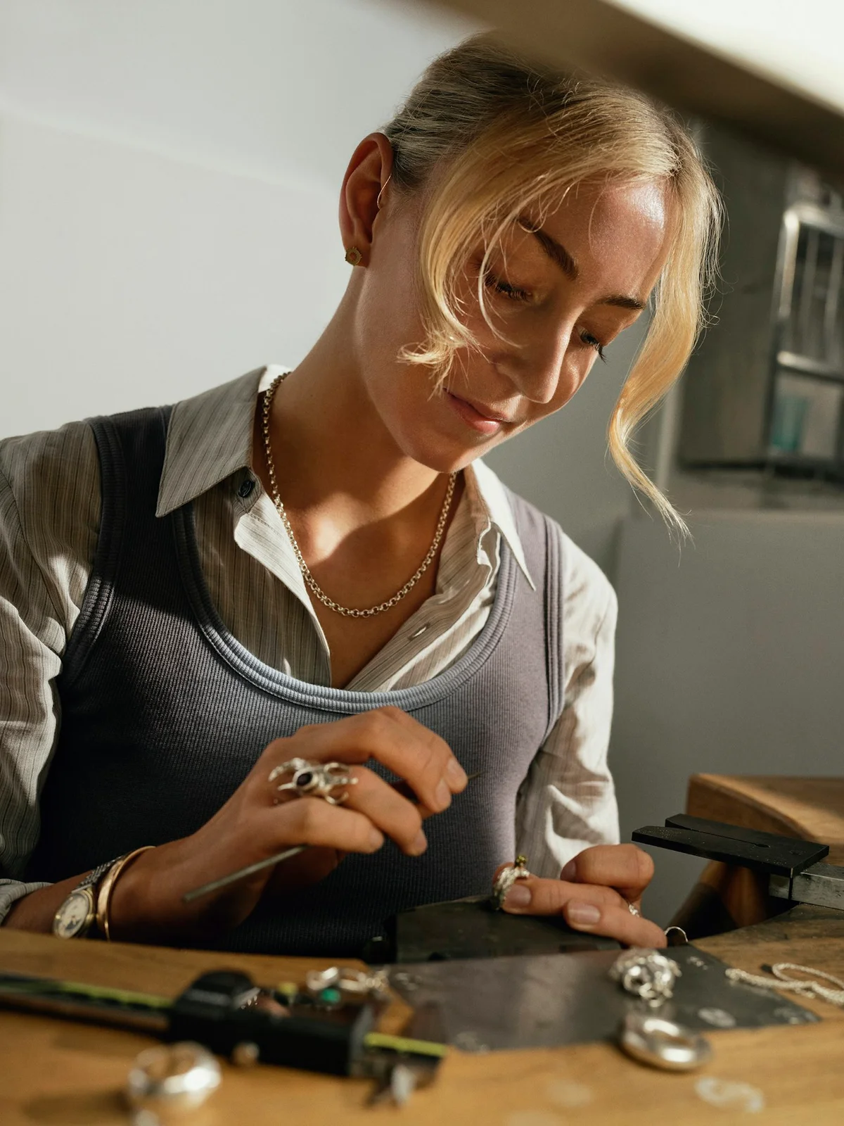 A jeweller working on a pendant at a workbench.
