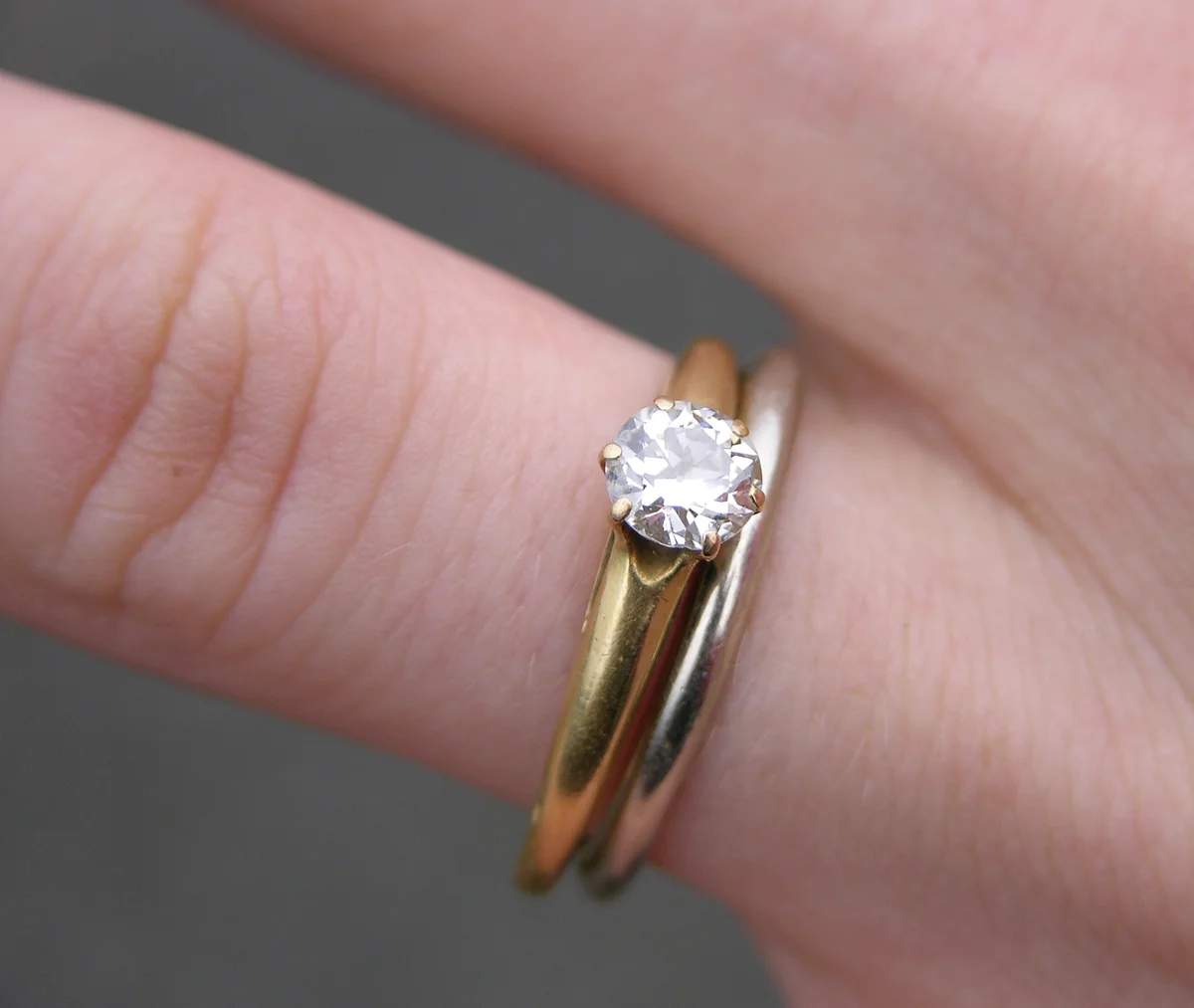 Six-prong diamond engagement ring photographed beside a wedding band.